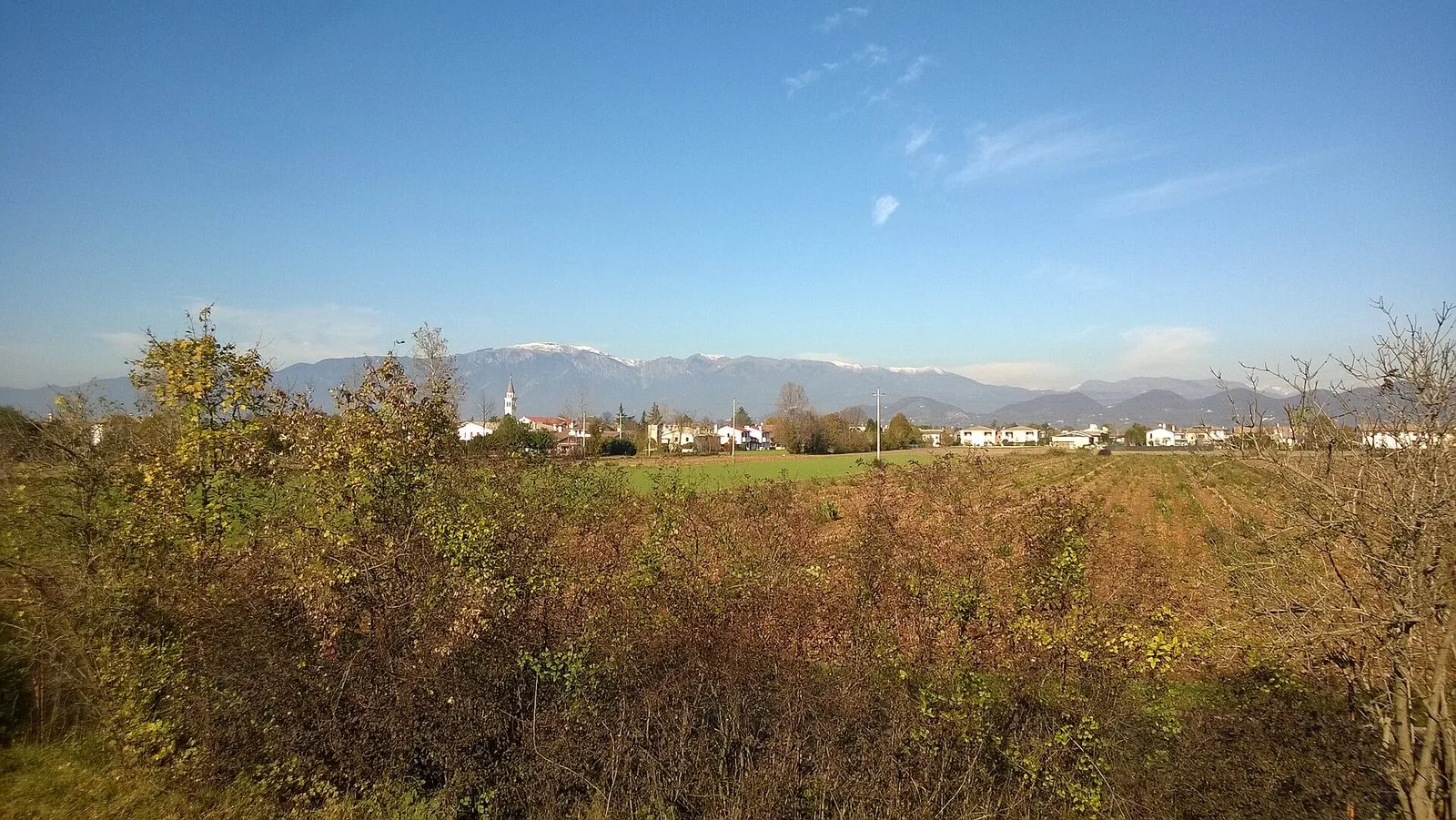 Il massiccio del Monte Grappa con le cime innevate visto dalla campagna della pianura in una giornata limpida d'autunno