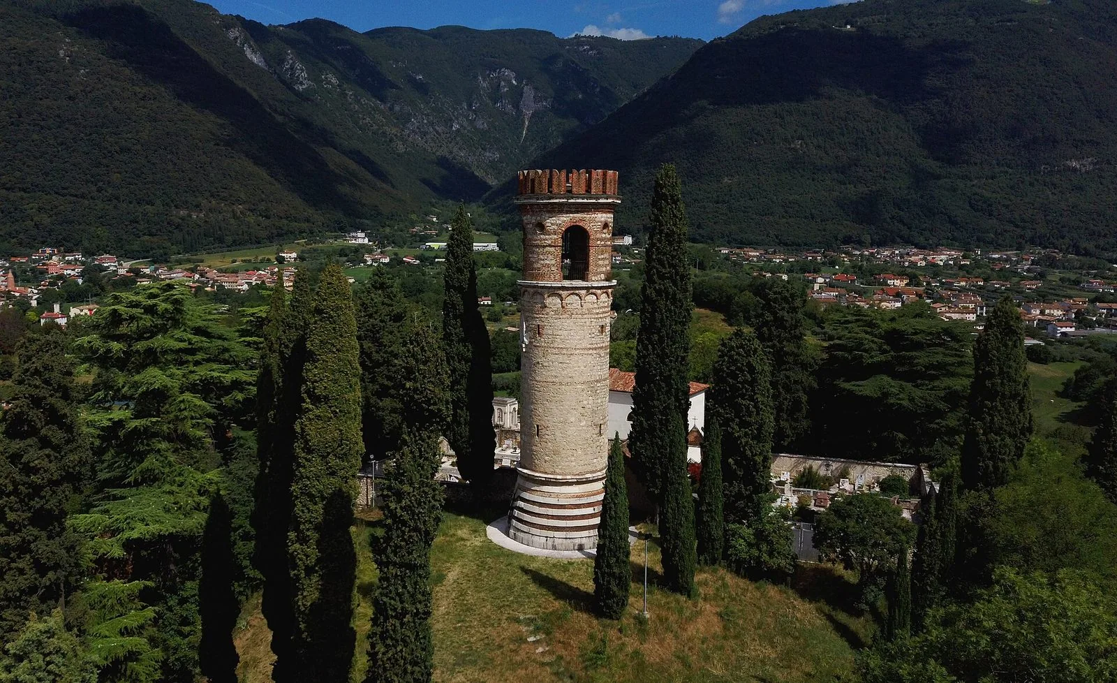 La Torre Ezzelina sul Col Bastia di Romano d'Ezzelino, circondata da cipressi, con le pendici boscose del Grappa sullo sfondo